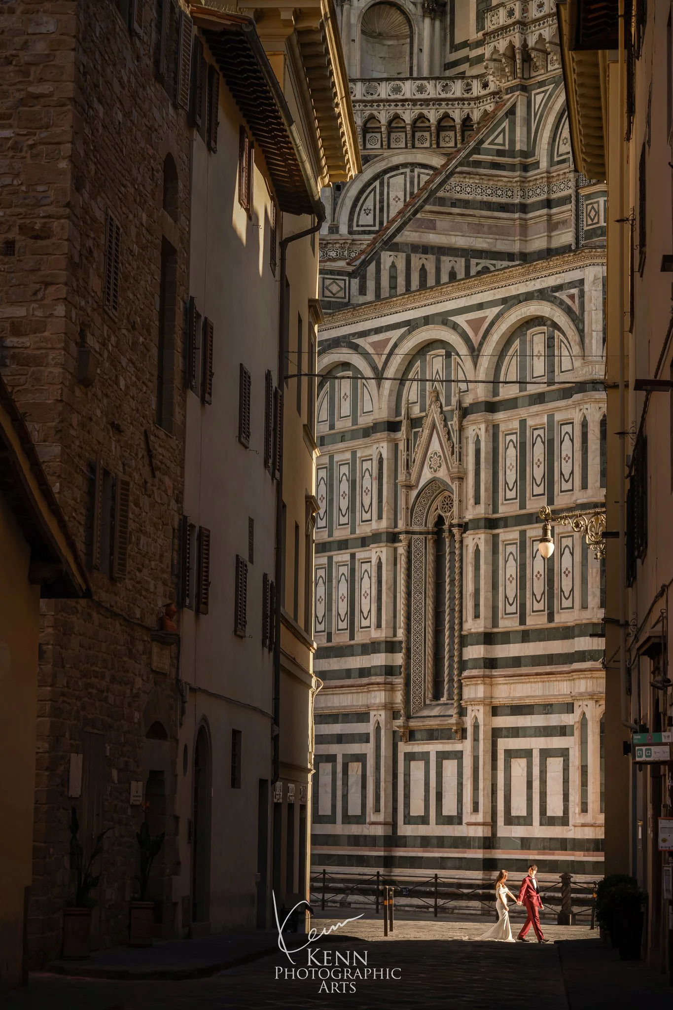 Wincy & Leo small in a tall Florentine lane framing the Duomo’s marble façade — Florence & Tuscany pre-wedding by Kenn Photographic Arts