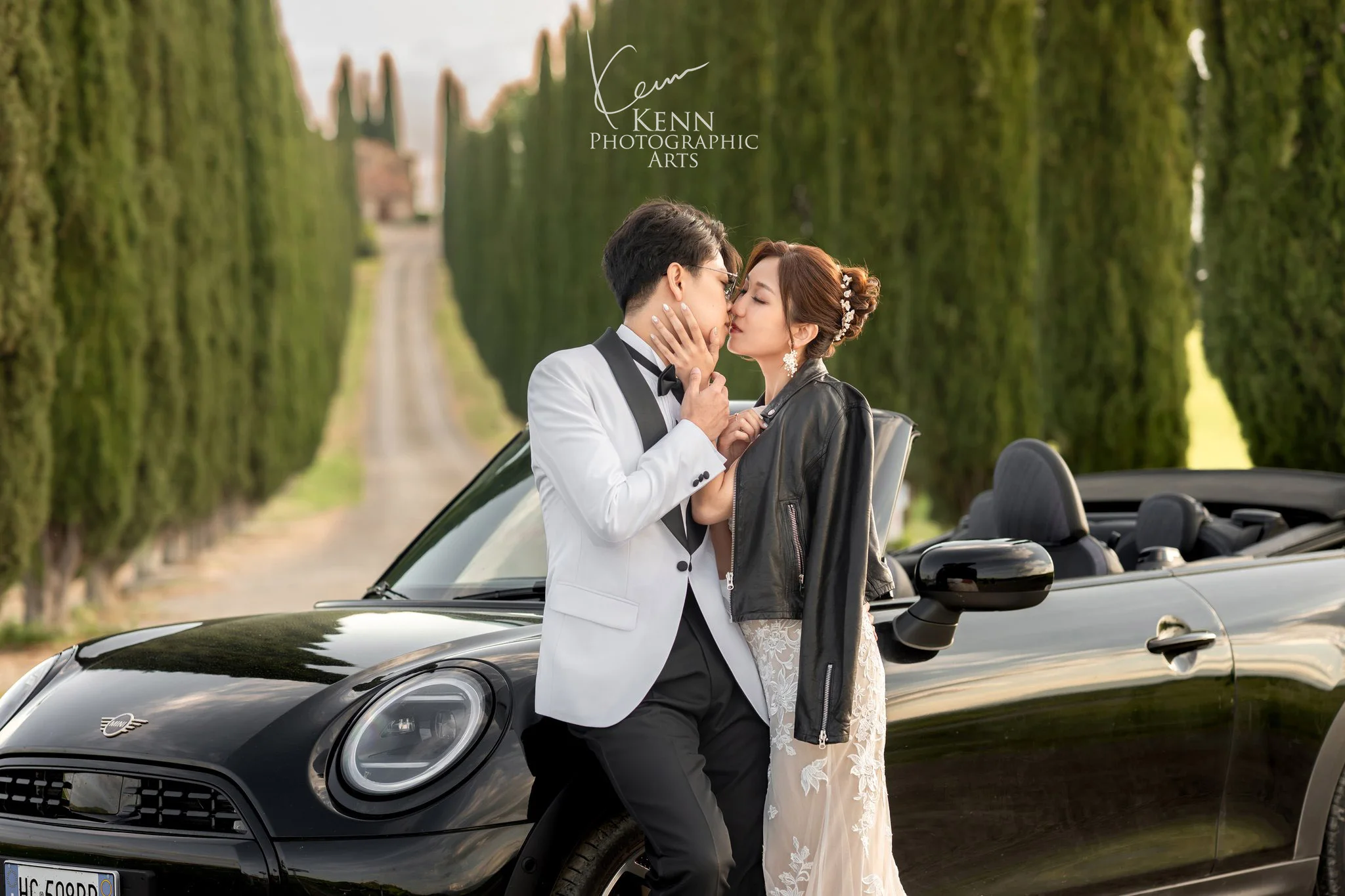 Wincy & Leo kissing beside the convertible on a cypress road — Florence & Tuscany pre-wedding by Kenn Photographic Arts