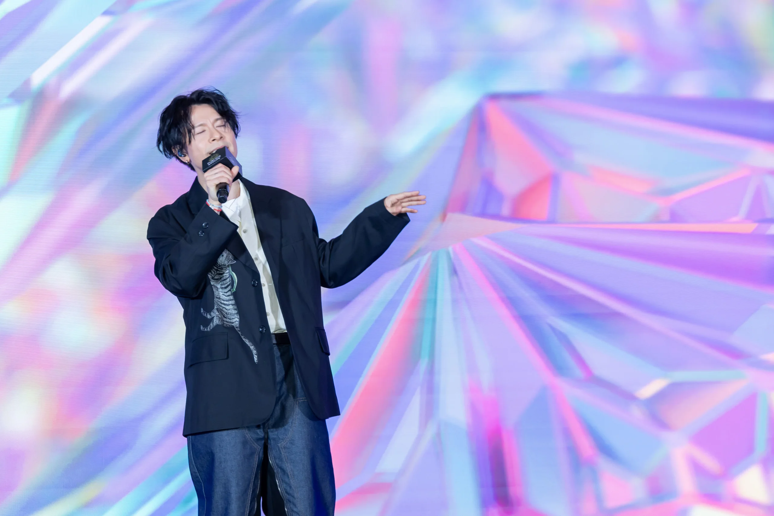 Singer performing on stage against a holographic backdrop — event photography by Kenn Photographic Arts