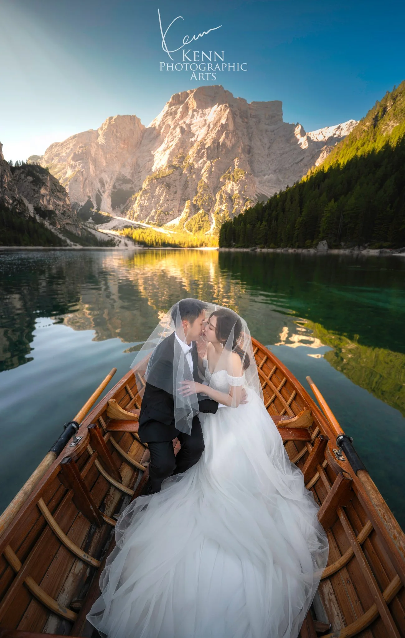 Mable & Hon kissing in a wooden rowboat on Lago di Braies — Dolomites pre-wedding by Kenn Photographic Arts