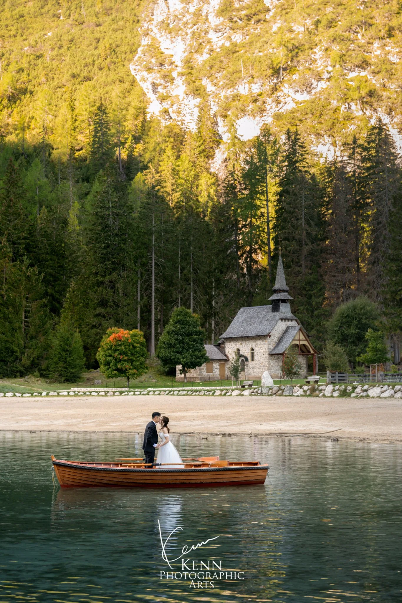 The lakeside chapel of Lago di Braies with the couple in a red rowboat — Dolomites pre-wedding by Kenn Photographic Arts