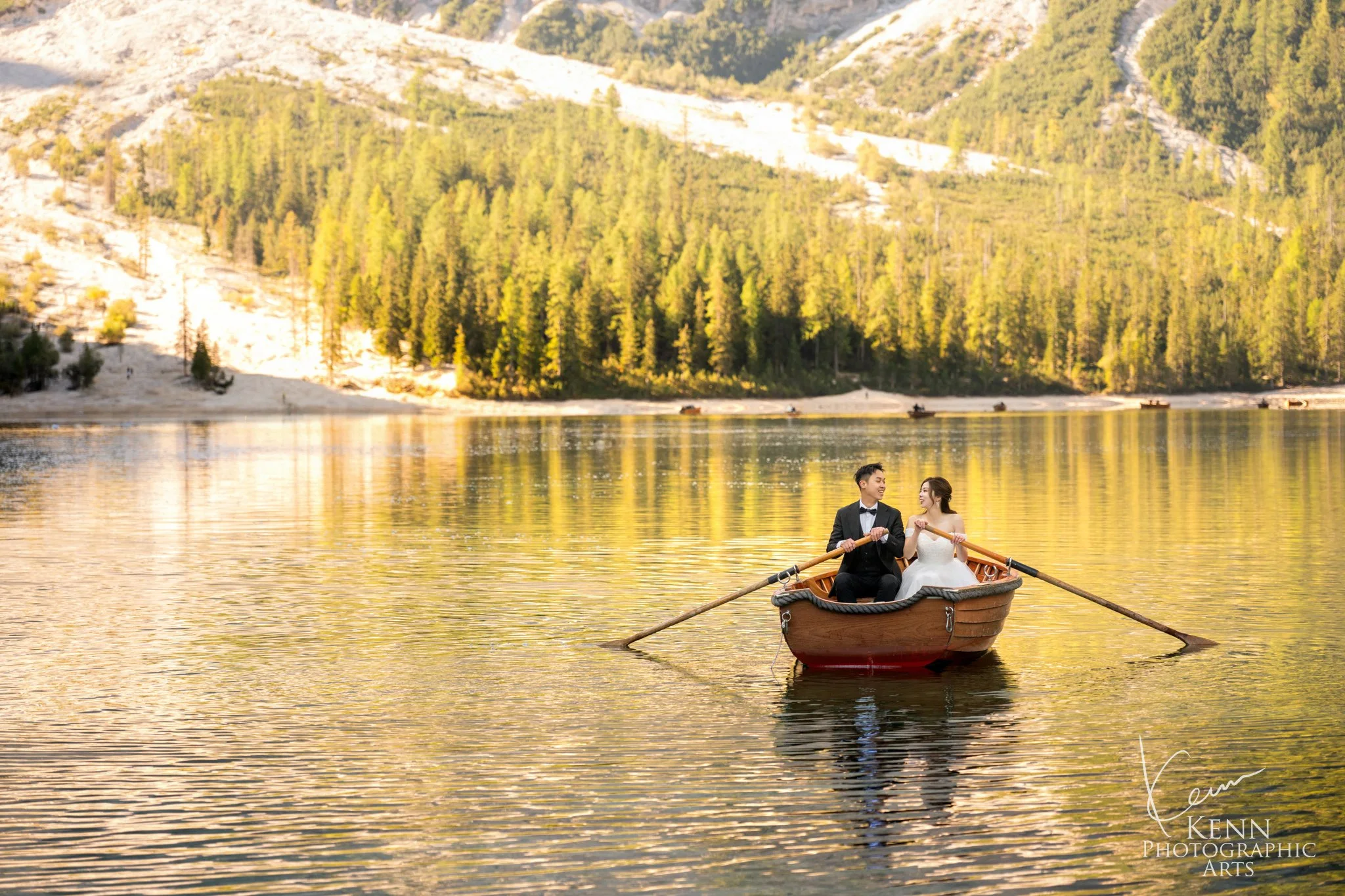 Mable & Hon in a rowboat on golden morning water — Dolomites pre-wedding by Kenn Photographic Arts