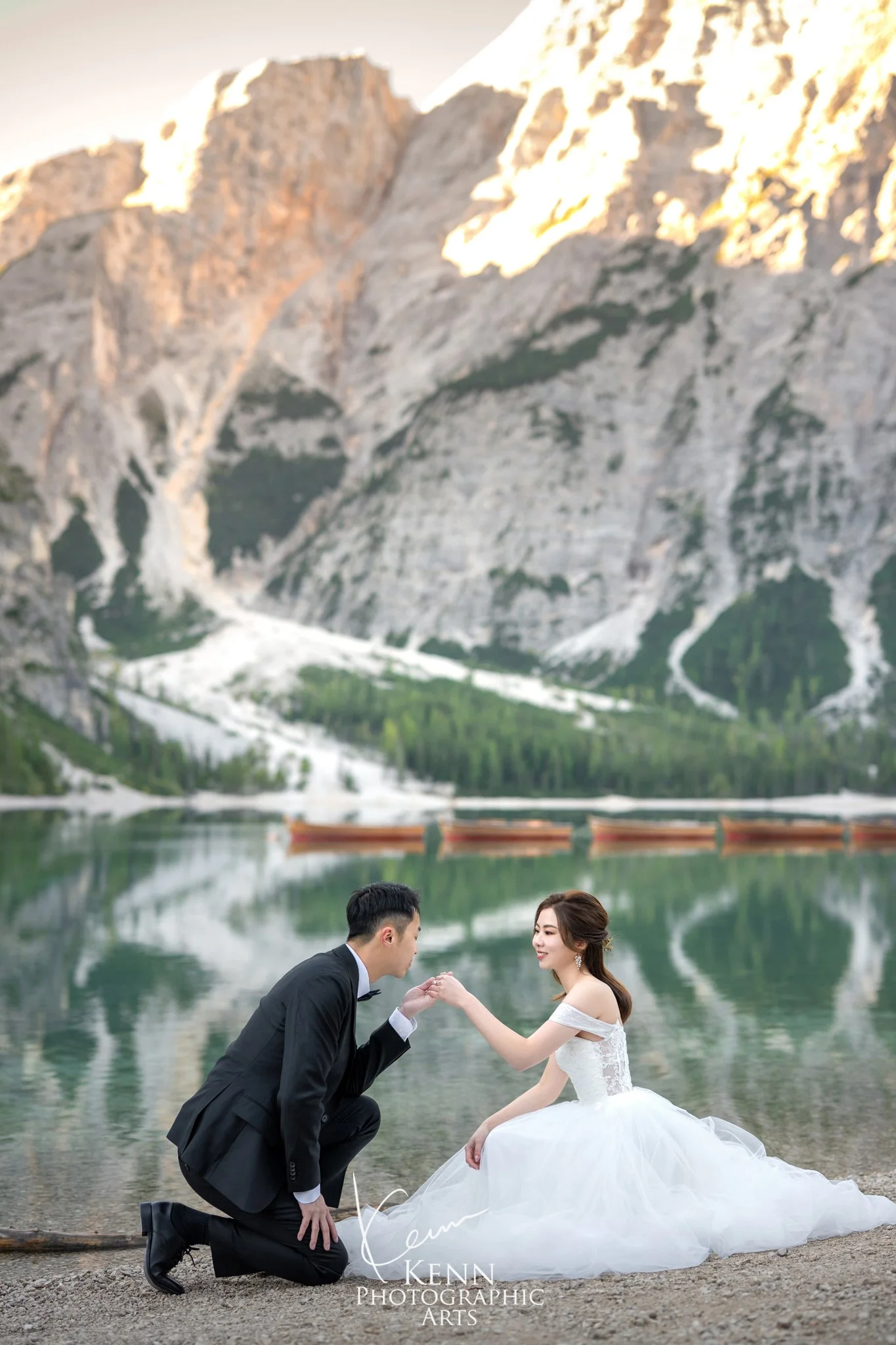 Hon kneeling to kiss Mable's hand by Lago di Braies — Dolomites pre-wedding by Kenn Photographic Arts