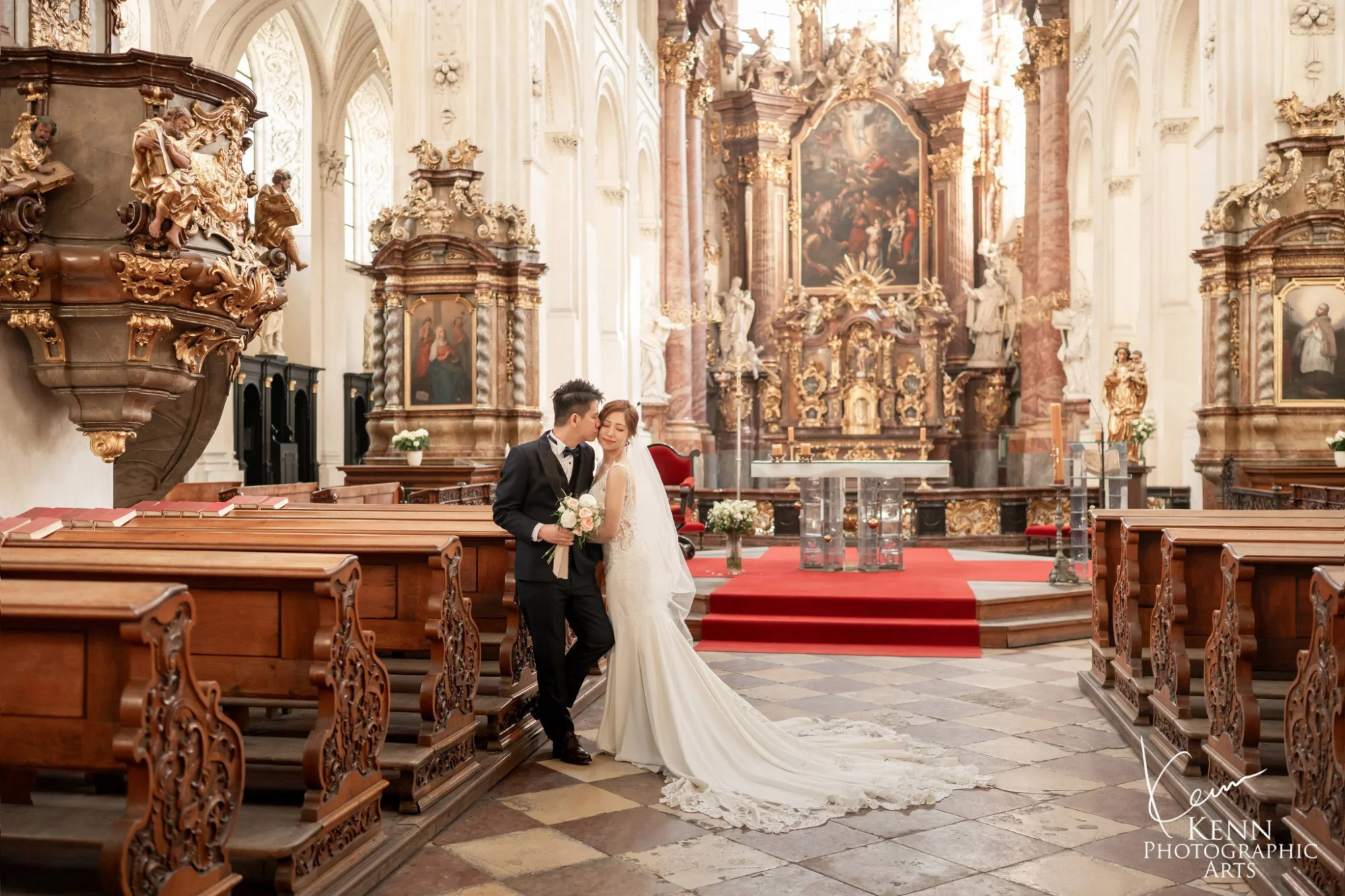 Yan & Victor in a gilded Baroque church interior, her long cathedral train across the floor — Prague pre-wedding by Kenn Photographic Arts