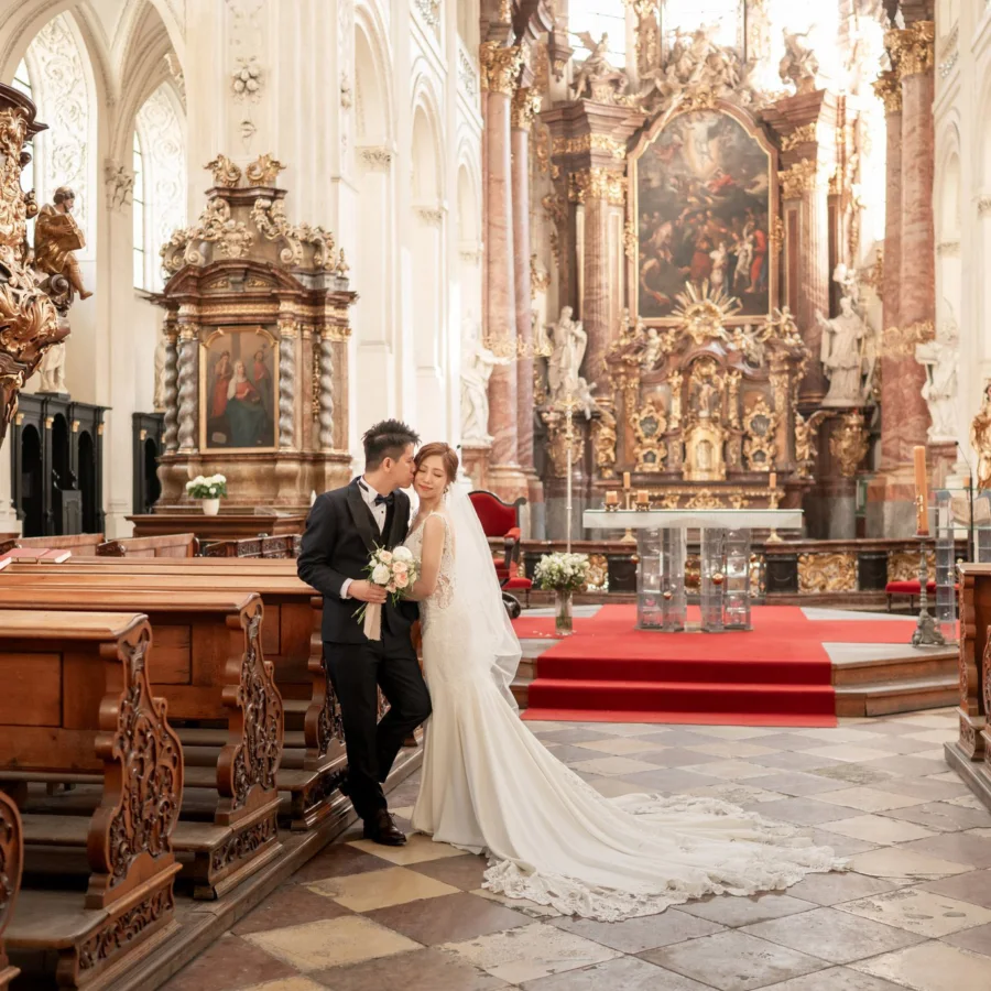 Yan & Victor in a gilded Baroque church interior, her long cathedral train across the floor — Prague pre-wedding by Kenn Photographic Arts